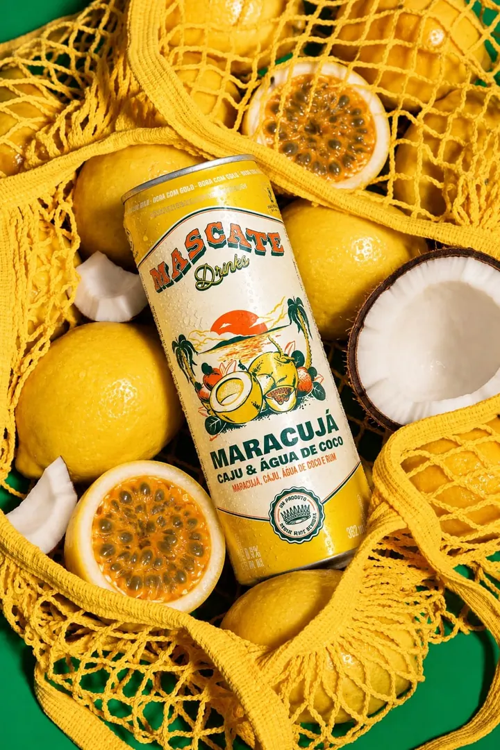 Lata Mascate Maracujá numa sacola de feira amarela com limões, maracujás e coco, sobre fundo verde